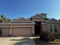 Front exterior of a single-story tan home with three-car garage and manicured landscaping at 10212 Holland Rd, Riverview, FL 33578