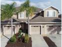 Exterior of a two-story townhome featuring a two-car garage, beige paint, and decorative landscaping at 10329 Willow Leaf Trl, Tampa, FL 33625