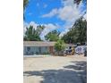 A single-story home with a neutral exterior surrounded by lush greenery, set on a gravel lot under a bright sky at 1114 27Th Se St # A, Ruskin, FL 33570