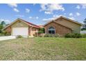 Single-story home featuring brick accents, light yellow siding, and a well-manicured front yard at 12371 Talpa St, Spring Hill, FL 34608
