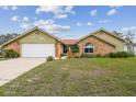 Charming single-story home featuring brick accents, light yellow siding, and a well-manicured front yard at 12371 Talpa St, Spring Hill, FL 34608
