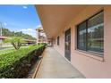 Exterior hallway featuring a covered walkway, well-maintained landscaping and easy access to parking at 143 Lakeside Dr # 143, Oldsmar, FL 34677