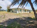 Single-story home with a chimney and large lawn in need of care, viewed from under a palm tree at 1447 Lemon Bay Dr, Englewood, FL 34223