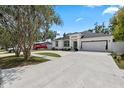 Wide view of a single-story home boasting a spacious driveway and neat landscaping against a blue sky backdrop at 19212 Sunlake Blvd, Lutz, FL 33558