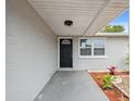 Inviting front porch with a modern black door, accent plants, and fresh mulch leading to a well-lit entrance at 2252 Society Dr, Holiday, FL 34691