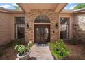 Close-up of double front door framed by brick archway, black sconces, and manicured potted plants at 2963 Cielo N Cir, Clearwater, FL 33759