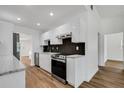 Modern kitchen with sleek white cabinets, stainless steel appliances, black backsplash, and stylish wood flooring at 3151 6Th S Ave, St Petersburg, FL 33712