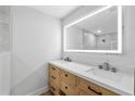 Bathroom featuring a double vanity, wood cabinets, and a large LED mirror at 3910 W Iowa Ave, Tampa, FL 33616