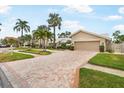 Brick driveway leads to a two-car garage, landscaped front yard and charming light-colored home at 4138 Saltwater Blvd, Tampa, FL 33615