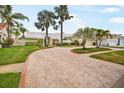 Brick driveway leads to a well-maintained light-colored home with a lush, landscaped yard at 4138 Saltwater Blvd, Tampa, FL 33615