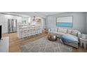 Open-concept living room and kitchen, featuring modern decor, stainless steel appliances, and seating for the kitchen island at 608 Betmor Ln, Palm Harbor, FL 34683