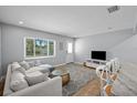 Cozy living room showcasing a comfortable sectional sofa, a large window, a TV, and access to an outdoor space at 608 Betmor Ln, Palm Harbor, FL 34683