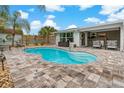Inviting backyard pool featuring a spacious paver patio and covered seating area, perfect for relaxation at 7909 Canna Dr, Port Richey, FL 34668