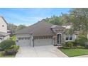 An eye-level shot of the property showcases stone details, a well-kept lawn and a three-car garage at 8015 Hampton Glen Dr, Tampa, FL 33647