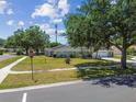 Landscaped front lawn featuring a charming single story brick home with an attached garage and shade trees at 10408 Butia Pl, Tampa, FL 33618