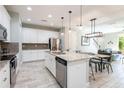 Bright kitchen boasts white cabinetry, stainless steel appliances, and an island with granite countertops at 17847 Althea Blue Pl, Lutz, FL 33558