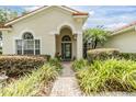 Charming front entrance featuring a beautifully landscaped walkway, arched entryway, and glass front door at 18002 Avalon Ln, Tampa, FL 33647