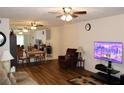 Bright living room with ceiling fan, hardwood floors, television and adjacent dining area at 2020 World Parkway Blvd # 12, Clearwater, FL 33763