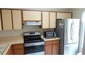 Efficient kitchen layout with stainless steel refrigerator, microwave, and updated oven range at 4736 Sunny Loop, Holiday, FL 34690