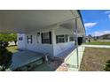 Exterior view of the home, showcasing white siding, green shutters, and a covered carport, adding curb appeal at 5318 Mary St, Zephyrhills, FL 33542