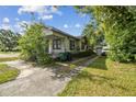 View of the home's side featuring a long driveway leading to a detached garage and lush greenery at 702 W Virginia Ave, Tampa, FL 33603