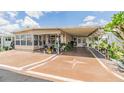 Inviting single-story home featuring a covered carport and a decorated porch with cozy seating at 7053 El Conquistador St, Zephyrhills, FL 33541