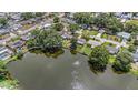 Scenic aerial view of a tranquil lake surrounded by homes, lush greenery, and mature trees at 1179 Lazy Lake W Rd, Dunedin, FL 34698