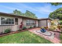 Attractive single-story home with colorful landscaping, brick accents, and a tranquil fountain feature at 1179 Lazy Lake W Rd, Dunedin, FL 34698