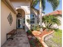 Inviting entrance with lush landscaping, a decorative bench, and arched doorway at 1228 Dartford Dr, Tarpon Springs, FL 34688