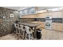 Eat-in kitchen with an island counter and seating, mosaic tile backsplash, and wood-look flooring at 13440 Gulf Blvd # 501, Madeira Beach, FL 33708