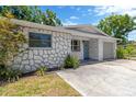 Charming single-story home boasts stone accents, a well-maintained lawn, and an attached garage with a concrete driveway at 1726 York S St, Gulfport, FL 33707