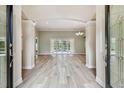 Spacious living room featuring light wood floors, columns, and sliding glass doors to the pool area at 19106 Beckett Dr, Odessa, FL 33556