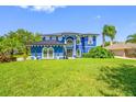 Bright blue two-story home with a well-manicured lawn under a clear blue sky at 19620 Eagle Crest Dr, Lutz, FL 33549
