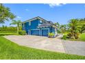 View of a bright blue home featuring an attached three-car garage and manicured landscaping at 19620 Eagle Crest Dr, Lutz, FL 33549