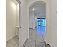 Hallway featuring an arched entryway, neutral walls, and tile flooring at 2882 Peony Prairie Ln, Wesley Chapel, FL 33543