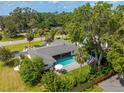 An aerial view of the home featuring a private pool, lush landscaping, and mature trees at 3236 San Pedro St, Clearwater, FL 33759