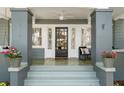 Close up of front porch with seating and potted plants flanking the black paneled door at 516 14Th Ne Ave, St Petersburg, FL 33701