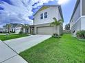A view of the house with a well-manicured lawn and a large driveway leading to the two-car garage at 7554 Wallflower Trl, Wesley Chapel, FL 33545
