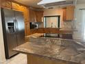 Spacious kitchen featuring stainless steel refrigerator, wood cabinets, and central island cooktop at 8209 Chaucer Dr, Weeki Wachee, FL 34607