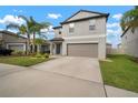Charming two-story home with a large driveway, well-manicured lawn, and lovely tropical landscaping at 9640 Lemon Drop Loop, Ruskin, FL 33573