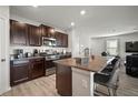 Open-concept kitchen with dark wood cabinets, stainless steel appliances, and a granite island with bar seating at 9640 Lemon Drop Loop, Ruskin, FL 33573