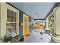 Inviting covered front porch featuring a yellow front door, swing, and ample seating area at 1402 E Powhatan Ave, Tampa, FL 33604