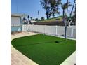 Backyard with a white picket fence and lush, green synthetic grass at 319 Boca Ciega Dr, Madeira Beach, FL 33708