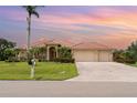 Beautiful single-story home featuring a terracotta roof, lush landscaping, a brick-paved driveway, and a two-car garage at 6120 9Th Avenue Ne Cir, Bradenton, FL 34212