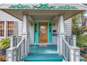 Inviting front porch with decorative trim, turquoise accents, and a wood door with glass panes at 7427 4Th N Ave, St Petersburg, FL 33710