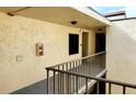 Exterior hallway featuring stucco walls, bronze railing, and an extinguisher on the wall at 2205 Belleair Rd # A36, Clearwater, FL 33764