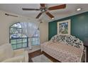 A well-lit room with an arch window, ceiling fan, floral bedding, and hardwood floors at 22115 Laver Ln, Land O Lakes, FL 34639
