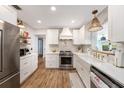 Bright kitchen featuring white cabinets, stainless steel appliances, and stylish hardwood floors at 2353 Dora Dr, Clearwater, FL 33765