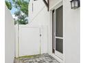 A white fence and entry door with screen leads to the main door, with manicured yard and exterior lighting at 308 S New Jersey Ave # A, Tampa, FL 33609