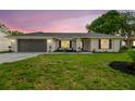 Charming single-story home at dusk with painted brick and attached two-car garage at 3205 Pleasant Lake Dr, Tampa, FL 33618